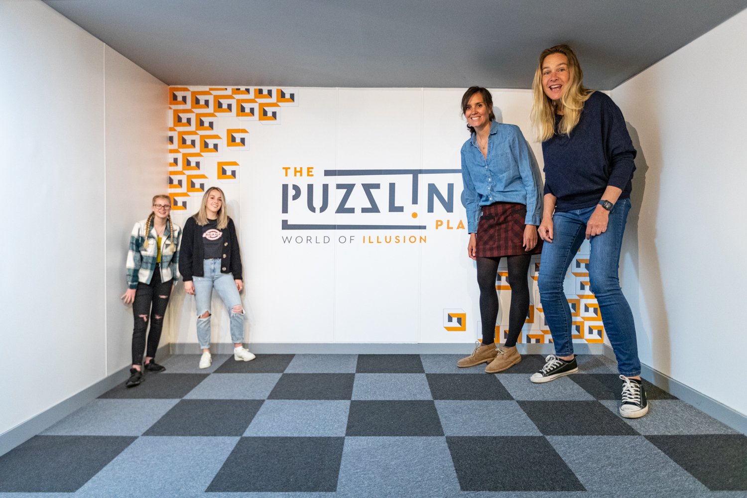 The Puzzling Place optical illusion room. Two women on the left appear to be bigger than the two women on the left.